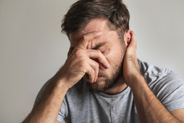 Grief and mental illness expression. Unhappy man with covered face with his hand.