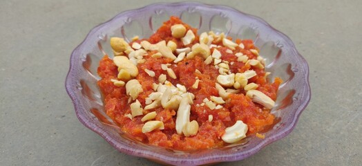 Fototapeta na wymiar Top view of Gajar halva with carrot, cashew, and pistachio nuts in a bowl on a gray background