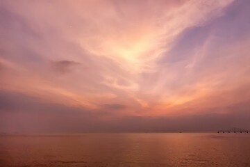 Naklejka na ściany i meble a bright sky over the ocean as the sun sets behind