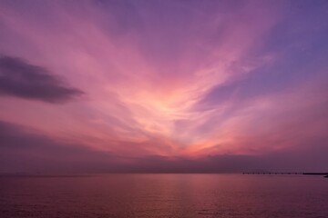 Fototapeta na wymiar the sun sets behind a bright purple sky over water and a small jett in the