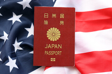 Japan passport on United States national flag background close up. Tourism and diplomacy concept