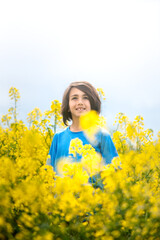 Fototapeta premium Child in the middle of a flowering field of rapeseed on a spring day.
