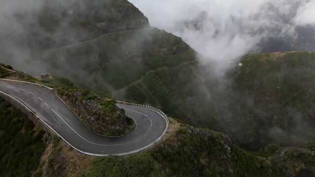 A beautiful road between green mountains with a cloudy sky in Lombo do Mouro, Portugal