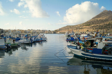Panorama con barche nel porto di favignana con sfondo di cielo azzurro e nuvole bianche sicilia...