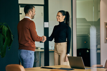 Business partners shaking hands after the meeting, male and female. - obrazy, fototapety, plakaty