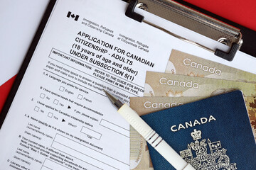 Application for Canadian citizenship for adults on table with pen, passport and dollar bills close...