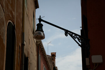 Close-up shot of a street lantern on the wall against clear blue sky background