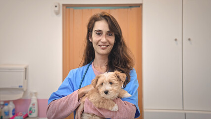 little dog visit veterinary clinic. Animal health care. Smiling veterinarian woman look at camera portrait. Nurse hold cute doggy. Pet vet job. Person check up puppy. Girl hug pup at healthcare lab.