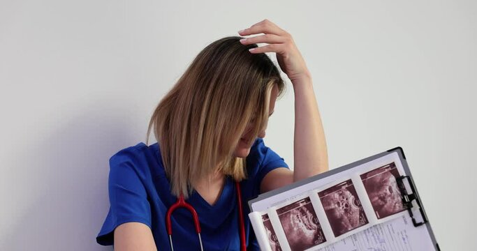 Exhausted female doctor examining the results of an ultrasound scan