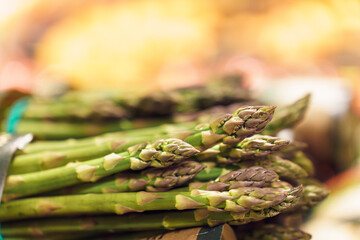 Close-up of bunches of green ripe asparagus on counter at market or grocery store in vegetable section