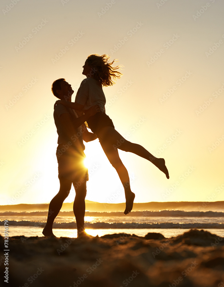 Wall mural Couple, love and happy at beach with sunset for date or summer holiday and bonding in Florida. Relationship, commitment and romance together as soulmate with smile, fun and lifting on vacation