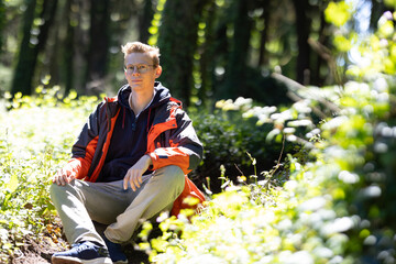 Boy Sitting on Rock in Woods