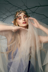 A young woman, dressed as a fairy-tale elf princess, stands with a veil gracefully draped over her...