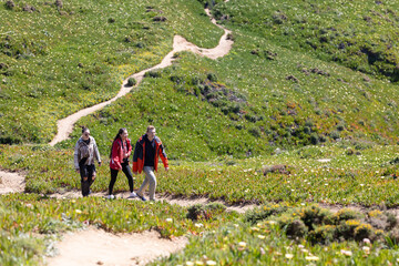 Three People Walking Up a Trail in the Mountains