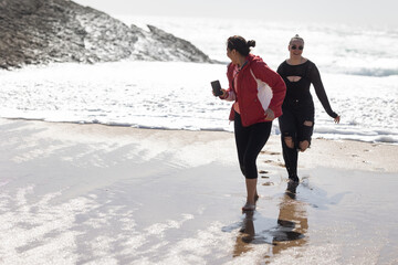Two Women Walking Along Beach Next to Ocean