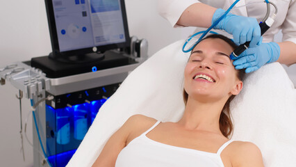 A middle-aged woman receives facial treatment in a professional beauty salon. A close-up...