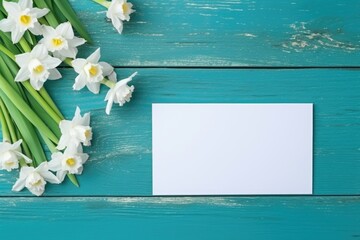 Fresh spring narcissus flowers by a blank card on a rustic turquoise wooden background. Spring Narcissus Flowers and Blank Card - obrazy, fototapety, plakaty