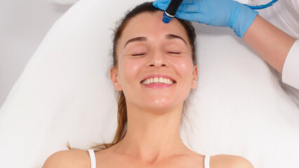 A middle-aged woman receives facial treatment in a professional beauty salon. A close-up...