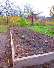 The garden bed with a border for growing vegetables in the garden is made of wide wooden planks.