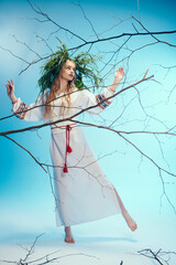 A young mavka in a traditional outfit holding branches in a magical studio setting.
