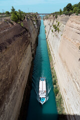 Tourist ship with Greek flag crosses the Corinth canal, the canal that separates Peloponnese from continental Greece, Europe.
