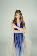 A young woman exudes elegance in a blue dress with a delicate veil, embodying the persona of an enchanting elf princess in a studio setting.