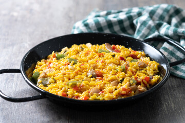 Yellow rice with chicken and vegetables on wooden table