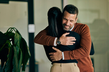 Business colleagues hugging each other after finishing a meeting with a big company. - 782989719