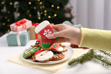 Woman with decorated Christmas cookie at table, closeup