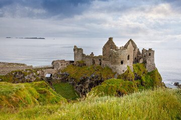 Ruins of Dunluce Castle, Antrim, Northern Ireland during sunny day with semi cloudy sky. Irish...
