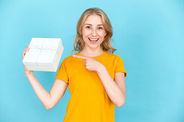 Smiling woman pointing by finger on gift box in hand