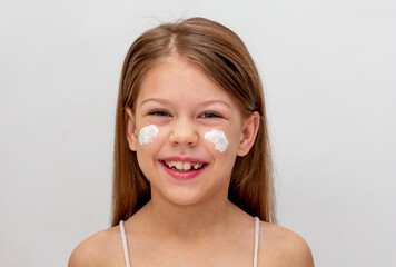 Portrait of smiling child with cream on cheeks as sun protection concept - obrazy, fototapety, plakaty