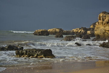 Photo of some waves crashing against the rocks on a beach in Portugal