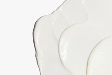 Fototapeta na wymiar White cosmetic cream smeared on a white background.