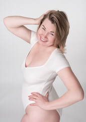 Mature adult woman looks so happy and confident in bodysuit, with one hand behind head and other on her hip. Concept of all about body positivity and embracing all shapes and sizes. High angle shot