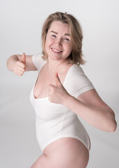 Portrait of plus size woman in bodysuit showing thumbs up, smiling and perfectly captures essence of body positive movement, celebrating all shapes and sizes with joy and enthusiasm. High angle shot