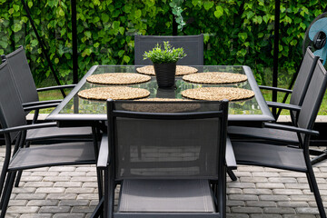 Gray metal table with 6 chairs outdoors in home garden.