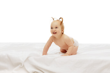 Portrait of happy little baby girl, toddlers with two ponytails sitting in diaper with playful happy face isolated on white background. Concept of childhood, care, health, well-being, parenthood