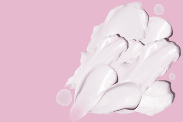 smears of cosmetic cream on a pink background.