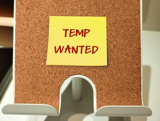 Stick note on board with text written TEMP WANTED - refers to trend of temporary employment,...