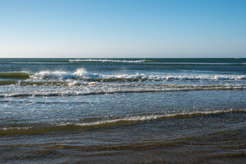 Detail of the waves of the Atlantic sea beating on the golden sand beach during the summer holidays in the province of Huelva, Spain.