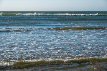 Detail of the waves of the Atlantic sea beating on the golden sand beach during the summer holidays in the province of Huelva, Spain.