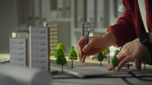 Architecture. A white European man dressed in work clothes carefully designs a residential area in the design department. Architect plans new residential area progressive urban landscape, house