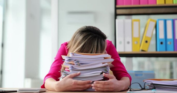Tired office worker is overloaded with paperwork in office
