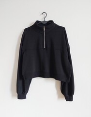 Black zip sweatshirt hanging on a hanger isolated on white background.