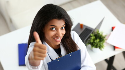 Female black doctor show OK or approval sign with thumb up portrait. High level service, best treatment 911 healthy lifestyle satisfied patient therapeutist consultation physical concept