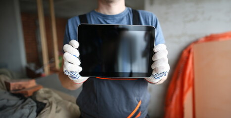 Close-up of specialist's hands showing high-tech gadget to camera. Builder wearing protective gloves and demonstrating empty display. Building concept. Copy space on screen