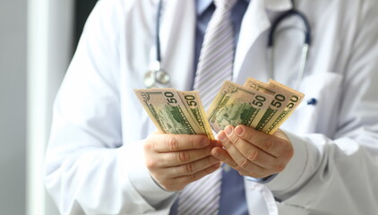 Male hand of doctor hald dollar cash in hand. Medical corrupt bribe concept