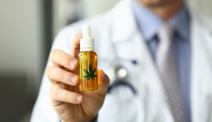 Male doctor hold bottle with marijuana oil medical hospital office closeup. Purpose narcotic drugs concept
