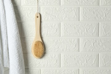 Bath accessories. Bamboo brush and terry towel on white brick wall, space for text